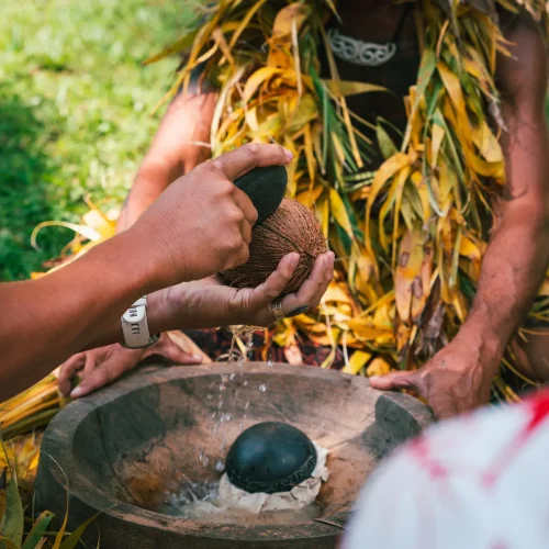 Guide accompagnant un visiteur pendant un atelier kava sur une plage de Tahiti