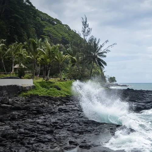 Vague se brisant sur les rochers noirs du Trou du Souffleur à Tahiti